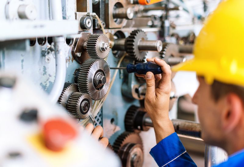 Technician inspecting and adjusting complex technical manufacturing equipment in Chicago, IL